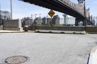there is a manhole on the curb of the street in front of the bridge