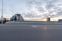 the sun rises over a city highway and a parking lot in front of a modern building