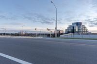 an empty street next to an overpass and city buildings with lights on it and the sky