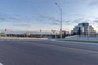 an empty street next to an overpass and city buildings with lights on it and the sky