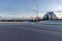 an empty street next to an overpass and city buildings with lights on it and the sky