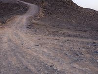 a truck on a dirt road in the desert with rocks and stones on the ground