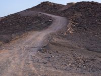 a truck on a dirt road in the desert with rocks and stones on the ground