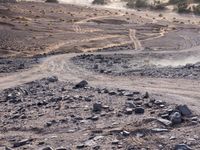 a truck on a dirt road in the desert with rocks and stones on the ground