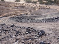 a truck on a dirt road in the desert with rocks and stones on the ground