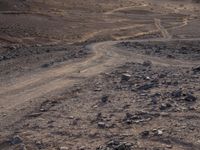 a truck on a dirt road in the desert with rocks and stones on the ground