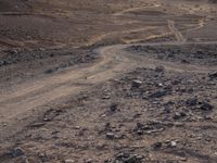 a truck on a dirt road in the desert with rocks and stones on the ground