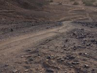 a truck on a dirt road in the desert with rocks and stones on the ground