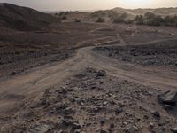 a truck on a dirt road in the desert with rocks and stones on the ground