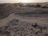 a truck on a dirt road in the desert with rocks and stones on the ground