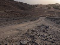 a truck on a dirt road in the desert with rocks and stones on the ground