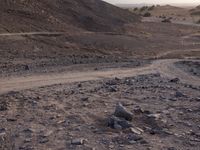 a truck on a dirt road in the desert with rocks and stones on the ground