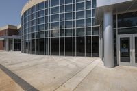 the large building is next to a tall glass windowed entrance and parking space on the sidewalk