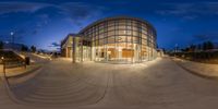 a wide shot shows the entrance and courtyard to a campus at night with lights on