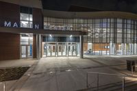 a night scene with a lit up entrance to the main school building on the college campus