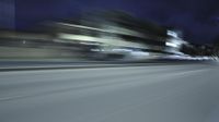 a car is moving down the street at night with blurry lights and a few cars passing by