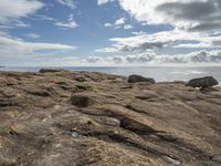 some rocks and the ocean is pictured here with a sky background and clouds in the distance