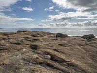 some rocks and the ocean is pictured here with a sky background and clouds in the distance