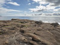 some rocks and the ocean is pictured here with a sky background and clouds in the distance