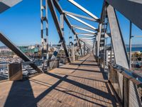 the bridge is metal in color and supports the street walkway with rails and traffic lights