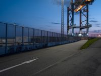 a very large metal bridge over a highway with lights on it's side at dusk