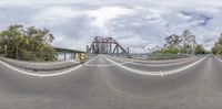 a long metal bridge crossing over a wide road in an image taken from the side