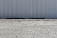 large metal structure behind a sandy area under cloudy skies of overcast sky and ocean