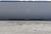 large metal structure behind a sandy area under cloudy skies of overcast sky and ocean