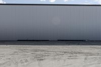 large metal structure behind a sandy area under cloudy skies of overcast sky and ocean