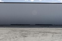 large metal structure behind a sandy area under cloudy skies of overcast sky and ocean