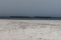 large metal structure behind a sandy area under cloudy skies of overcast sky and ocean