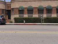 the parking meter in front of a large brick building with awnings and green canopy