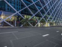 a street scene at dusk in front of a large building with a huge glass wall