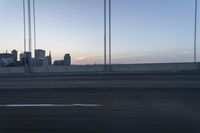 a city from a freeway driving over a bridge under construction in the sun set with clouds