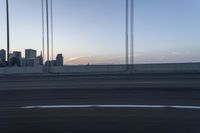 a city from a freeway driving over a bridge under construction in the sun set with clouds