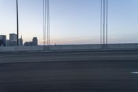 a city from a freeway driving over a bridge under construction in the sun set with clouds