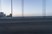 a city from a freeway driving over a bridge under construction in the sun set with clouds