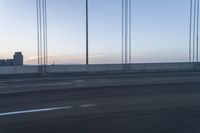 a city from a freeway driving over a bridge under construction in the sun set with clouds