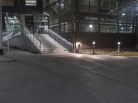 a lighted walkway outside a building with stairs on either side and stairs above the doorway