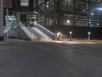 a lighted walkway outside a building with stairs on either side and stairs above the doorway