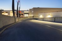 empty street with concrete fence and traffic lights in the dark at twilight time with a street lamp on pole