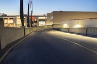 empty street with concrete fence and traffic lights in the dark at twilight time with a street lamp on pole