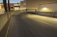 empty street with concrete fence and traffic lights in the dark at twilight time with a street lamp on pole