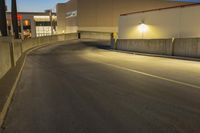 empty street with concrete fence and traffic lights in the dark at twilight time with a street lamp on pole