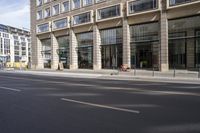 there is an empty street in a city with many windows and a bike parked at the curb