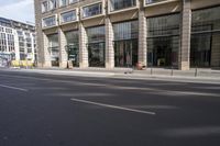 there is an empty street in a city with many windows and a bike parked at the curb