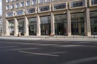 there is an empty street in a city with many windows and a bike parked at the curb