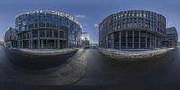 two circular buildings near one another with a sidewalk running between them in the middle of them