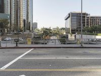 a city street in the day time with cars and buildings around it and a road crossing area that is blocked off from the sidewalk and parking lot
