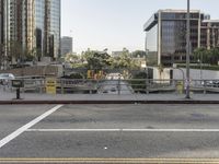 a city street in the day time with cars and buildings around it and a road crossing area that is blocked off from the sidewalk and parking lot